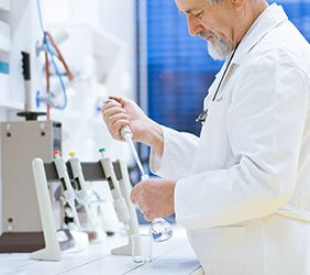 Senior male researcher carrying out scientific research in a lab using a gas chromatograph